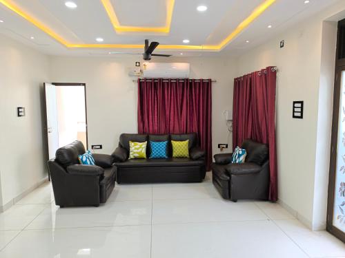 a living room with two couches and red curtains at Orraica Stays Vajra Rao Luxe in Gundipet