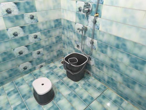 a blue tiled bathroom with a toilet and a shower at Orraica Stays Vajra Rao Luxe in Gundipet