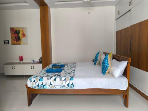 a bedroom with a bed with blue pillows on it at Orraica Stays Vajra Rao Luxe in Gundipet