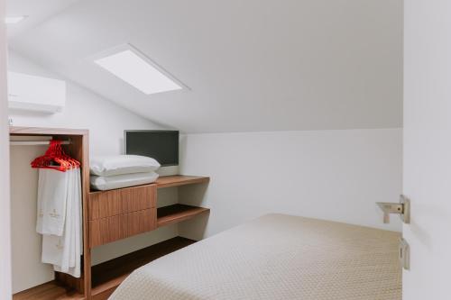 a bedroom with a bed and a shelf with towels at Belo Encanto in Felgueiras