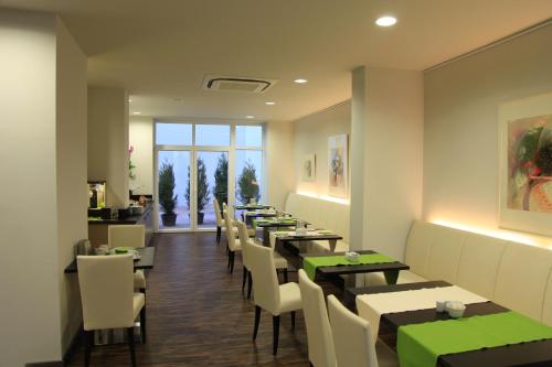 a dining room with tables and white chairs at Art Hotel Lauterbach in Kaiserslautern