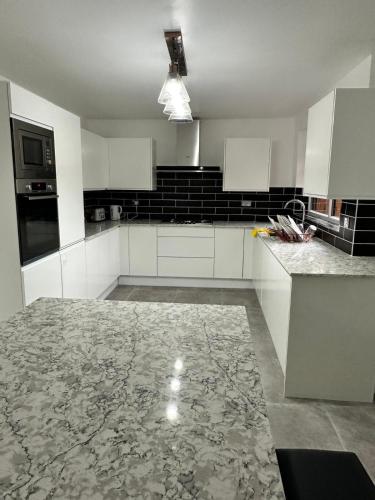 a kitchen with white cabinets and black appliances at Fairestone House in Glenfield