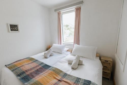 a bedroom with a bed with pillows and a window at SUN COTTAGE - Cosy Cottage in Ulverston with a log burner in Ulverston, Cumbria in Ulverston