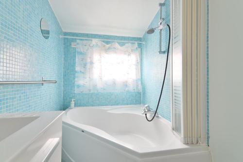 La salle de bains est pourvue d'une baignoire blanche et de carrelage bleu. dans l'établissement Studio Appartement Quartier Saint-Michel Notre-Dame 2 Free Netflix, à Paris