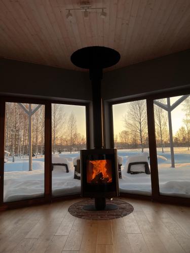 a fireplace in the middle of a room with windows at Dabas Osta in Jūdaži
