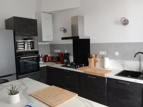 une cuisine avec des armoires noires et un comptoir blanc dans l'établissement La Ria, à Douarnenez