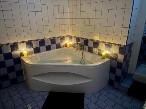 La salle de bains carrelée est pourvue d'une baignoire et de deux bougies. dans l'établissement Provence, à Digne-Les-Bains