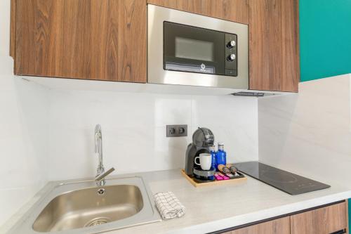 a kitchen counter with a sink and a microwave at Atw Suites Canteras in Las Palmas de Gran Canaria