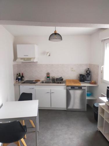 - une cuisine avec des placards blancs, un évier et une table dans l'établissement Cœur de ville, à Mont-de-Marsan