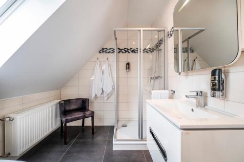 a bathroom with a shower and a sink and a chair at Seehotel Lichtenberg in Lichtenberg