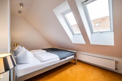 a bed in a room with two windows at Seehotel Lichtenberg in Lichtenberg