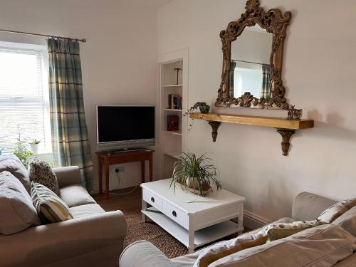 a living room with a couch and a mirror at Berry View - Idyllic cosy cottage on berry farm in Blairgowrie