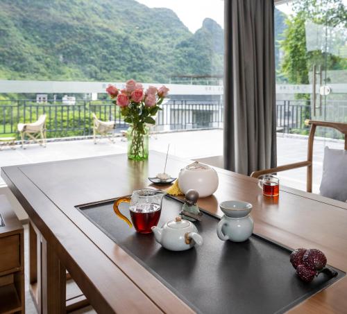 a table with a tea set on it with a vase of flowers at Yangshuo-Greenery Retreat in Yangshuo