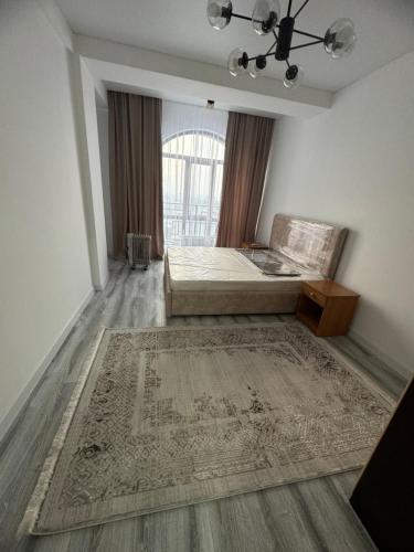 a bedroom with a bed and a rug and a window at Evita Apartment in Bishkek