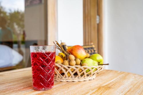 a drink in a glass next to a basket of fruit at Aura Apartments Ubud in Ubud