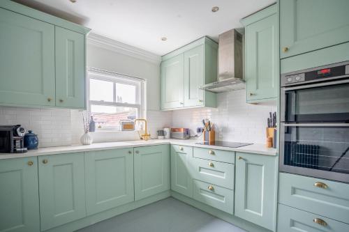 a green kitchen with white cabinets and a window at 7 Arndale Court in York