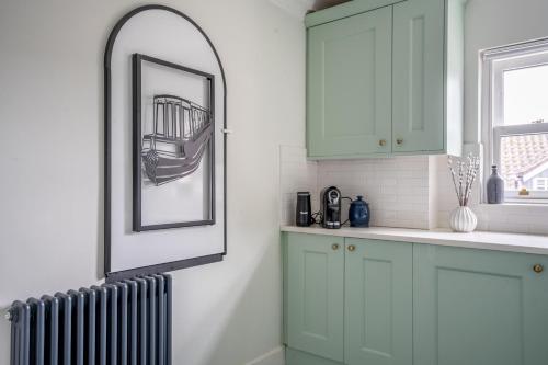 a kitchen with green cabinets and a mirror and a radiator at 7 Arndale Court in York
