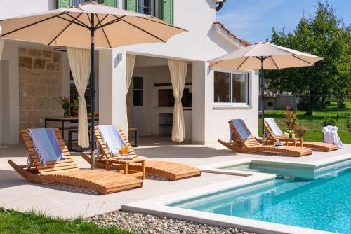 a group of chairs and umbrellas next to a pool at 2-bedroom Villa Providenca in Bajagić