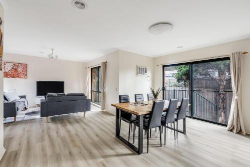 Una sala de estar con una mesa y sillas y un sofá. en Heart of McKinnon Units by Ready Set Host, en Melbourne