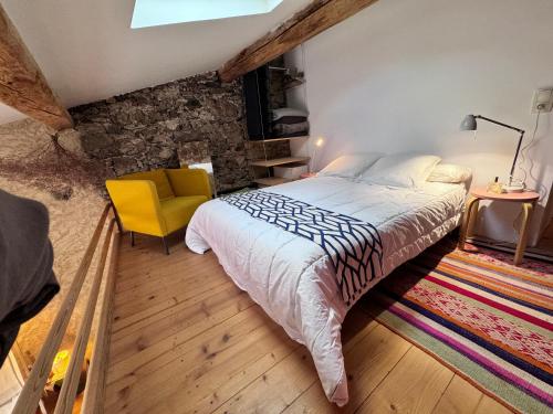 - une chambre avec un grand lit et une chaise jaune dans l'établissement La Maison du Fenil de Tende Vallee des Merveilles, à Tende