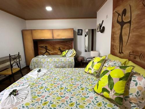a bedroom with two beds with yellow and green pillows at Flor de Limão Hotel Boutique in Coroa Vermelha