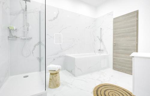 La salle de bains blanche est pourvue d'une douche et d'une baignoire. dans l'établissement Bluestay 287 - Superbe appartement à Paris 17, à Paris