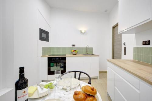 - une cuisine blanche avec une table et une bouteille de vin dans l'établissement Bluestay 287 - Superbe appartement à Paris 17, à Paris