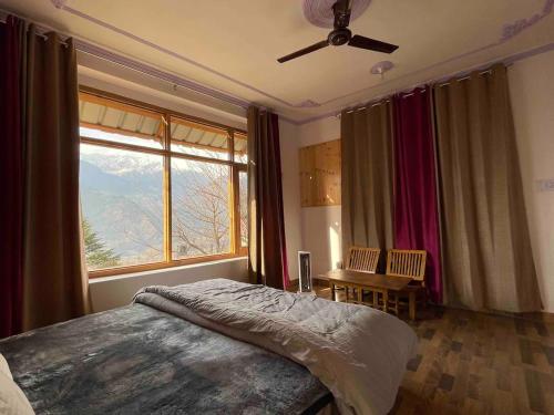 a bedroom with a bed and a large window at Kutumb Homestay Naggar in Nagar