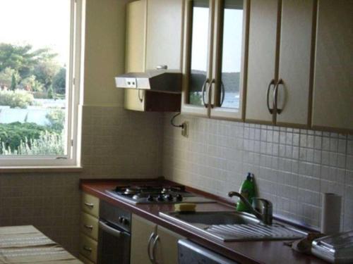 Una cocina con estufa, fregadero y ventana. en Apartment Mer, en Sevid