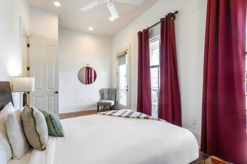 a bedroom with a large bed with red curtains at Fabulous Cottages with City Views in New Orleans