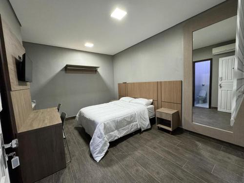 a bedroom with a white bed and a mirror at John- R Apart-hotel Curitiba Jardim Botânico in Curitiba