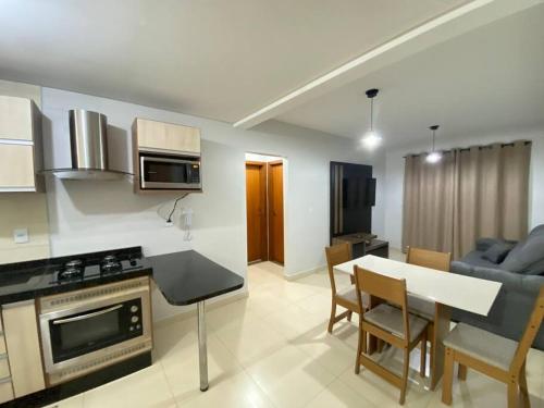 Il comprend une cuisine et un salon avec une table et un canapé. dans l'établissement Apartamento Inteiro - 2 Quartos com AC - Wifi 300mb - Cozinha Completa - 1 Vaga de Garagem - TV Smart 50 - Sacada - Indicado para Grupos, Hospedes a Trabalho, Família e Pets, à Toledo