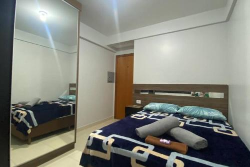- une chambre avec un miroir et un lit avec des oreillers dans l'établissement Apartamento Inteiro - 2 Quartos com AC - Wifi 300mb - Cozinha Completa - 1 Vaga de Garagem - TV Smart 50 - Sacada - Indicado para Grupos, Hospedes a Trabalho, Família e Pets, à Toledo