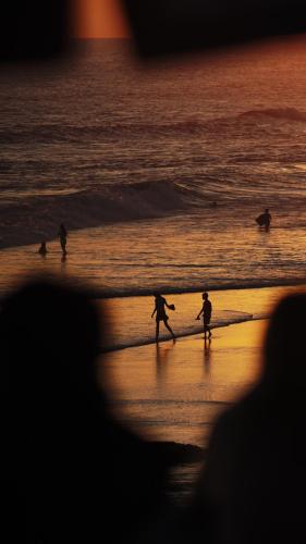 a group of people playing on the beach at sunset at Surf Motel in Canggu