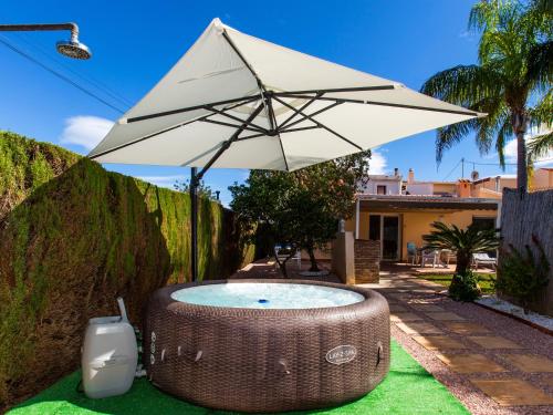 an umbrella and a wicker bathtub on the grass at Casa Marineta III in Denia