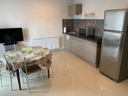 une cuisine avec une table et un réfrigérateur en acier inoxydable dans l'établissement Agréable appartement 2 pièces, à Pierrelaye
