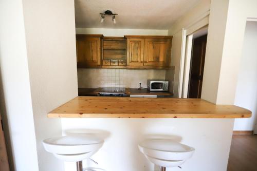 a kitchen with wooden cabinets and a counter with two stools at Chalet Alpina résidence Val Claret in Tignes