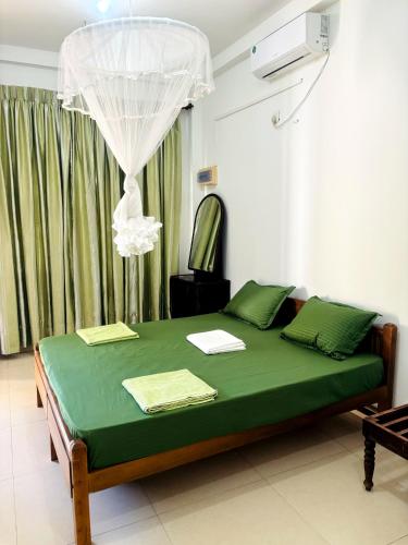 a bedroom with a green bed with a chandelier at Nihal Bay View in Matara
