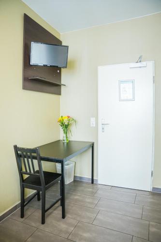 a black table with a chair and a television on a wall at Hotel City Star in Frankfurt/Main