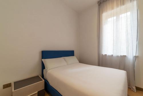 a white bed with a blue headboard and a window at JOIVY Cavour 238 in Rome