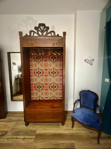 a cabinet with a quilt on it next to a blue chair at Sicily in Love - Rooms and Apartment - Pedara Catania Etna in Pedara