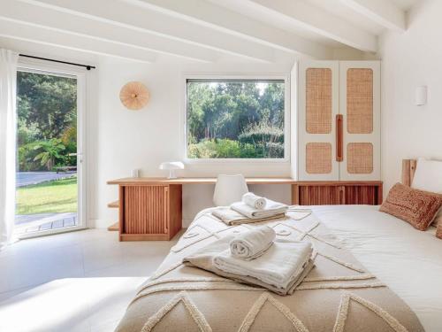 une chambre avec un grand lit avec des serviettes dessus dans l'établissement Villa avec piscine chauffée, jardin exotique, au calme proche plages et commerces, Capbreton - FR-1-791-17, à Capbreton