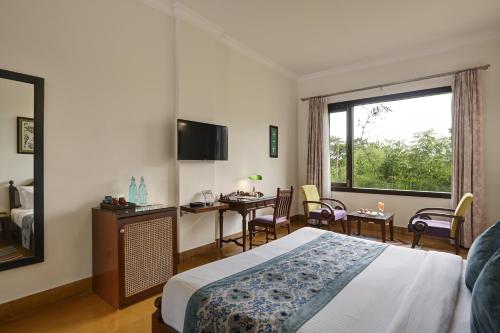 a hotel room with a bed and a desk and a window at Anandam - A Luxury Resort in Udaipur in Udaipur