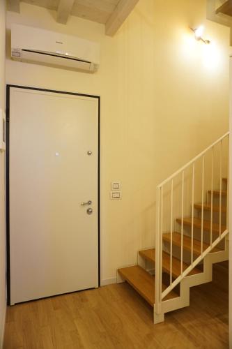 a door in a room with a staircase and a stair case at Cozy flat in Fontanellato