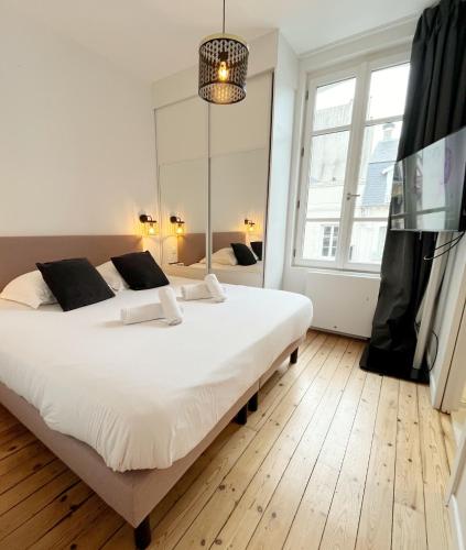 une chambre avec un grand lit blanc et une télévision dans l'établissement Le Albert Deauville, à Deauville