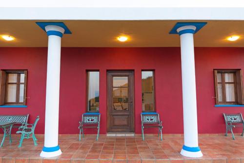 a red building with white columns and a door at Sirens Villas - Sea View Private Pool Villas in Skopelos Town