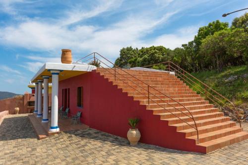 a red house with stairs on the side of it at Sirens Villas - Sea View Private Pool Villas in Skopelos Town