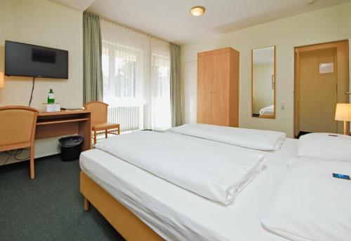 a hotel room with two beds and a desk and a mirror at Hotel Wiking in Kiel