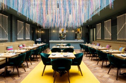 a restaurant with tables and chairs and colorful chandeliers at Sun Street Hotel Shoreditch in London