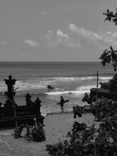 a person walking on the beach with a surfboard at Surf Motel in Canggu
